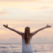 girl facing the ocean, hands reaching out