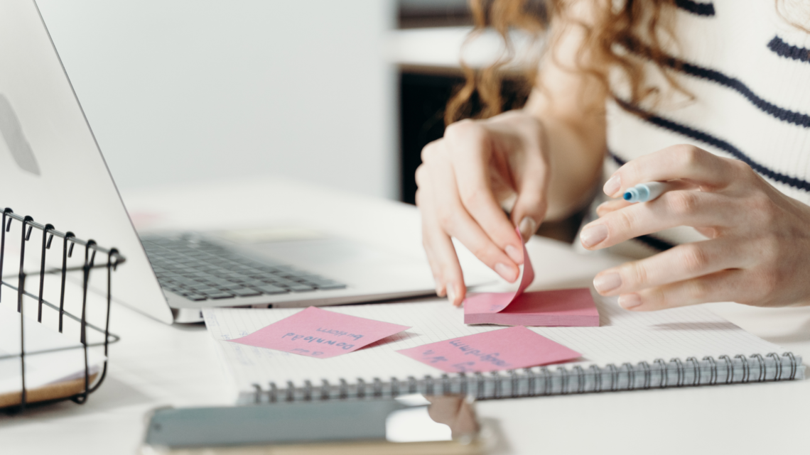 woman organising sticky notes in front of her laptop