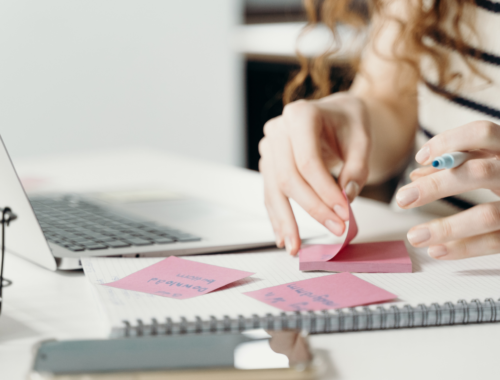 woman organising sticky notes in front of her laptop